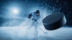 Hockey player hitting puck on the ice